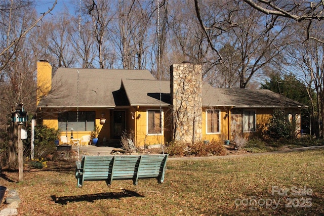 rear view of house featuring a chimney and a yard