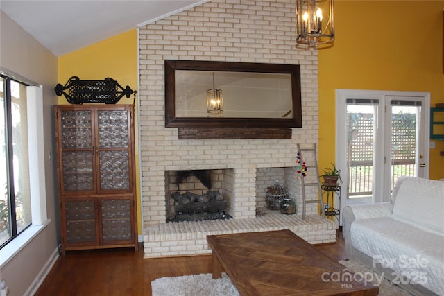 living room with lofted ceiling, a brick fireplace, and dark wood-style flooring