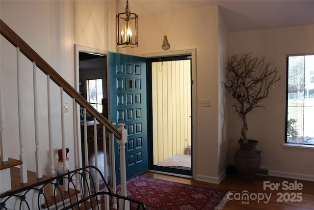 foyer featuring dark wood-type flooring, baseboards, an inviting chandelier, and stairs