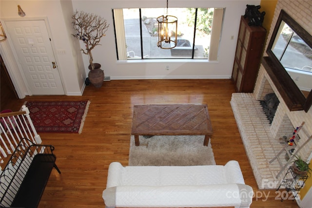 living room featuring baseboards, stairway, wood finished floors, an inviting chandelier, and a fireplace