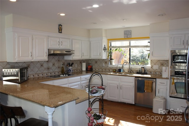 kitchen with stainless steel appliances, white cabinetry, a sink, a peninsula, and under cabinet range hood