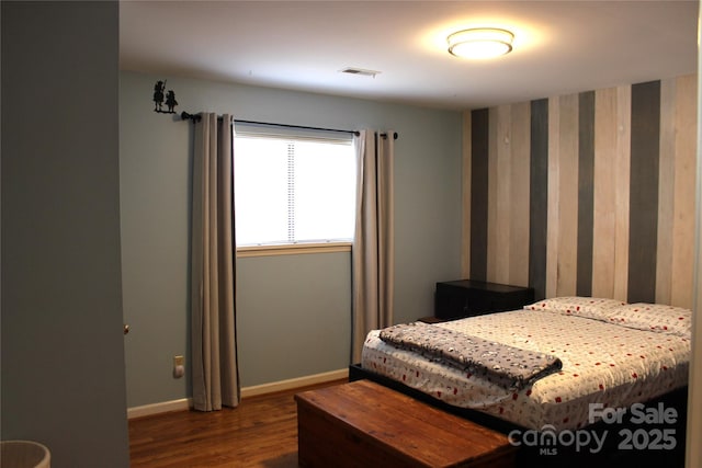 bedroom featuring visible vents, baseboards, and wood finished floors