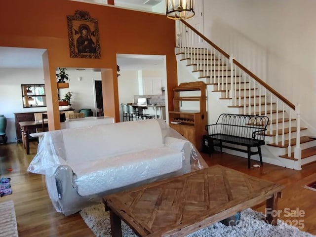 living area featuring stairs, a towering ceiling, and wood finished floors