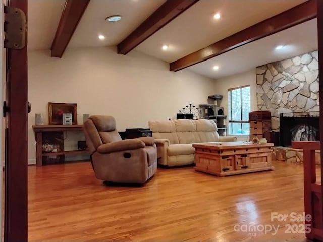 living room with lofted ceiling with beams, a stone fireplace, light wood-type flooring, and recessed lighting