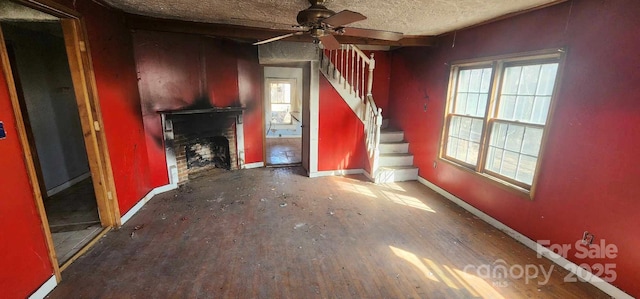 unfurnished living room featuring ceiling fan, a healthy amount of sunlight, and a textured ceiling