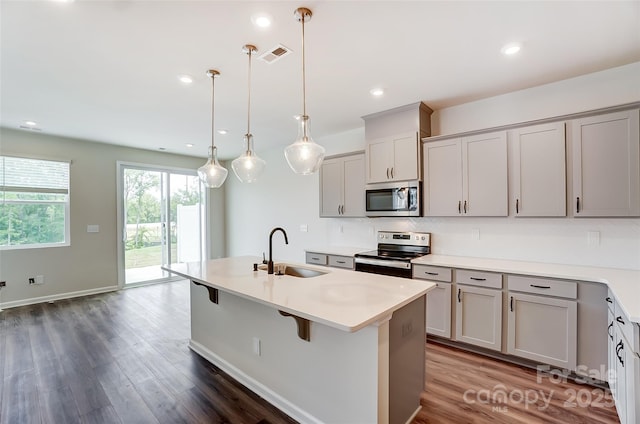 kitchen featuring gray cabinets, appliances with stainless steel finishes, pendant lighting, an island with sink, and sink