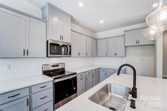 kitchen with stainless steel appliances, hanging light fixtures, sink, and light stone counters