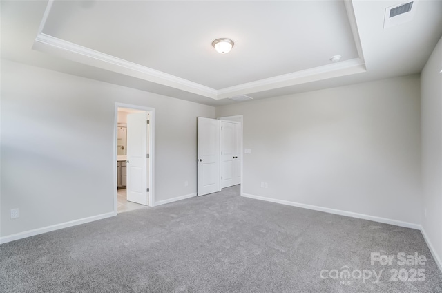 carpeted empty room with ornamental molding and a raised ceiling