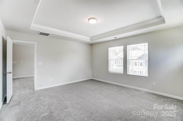 carpeted spare room featuring a tray ceiling and ornamental molding