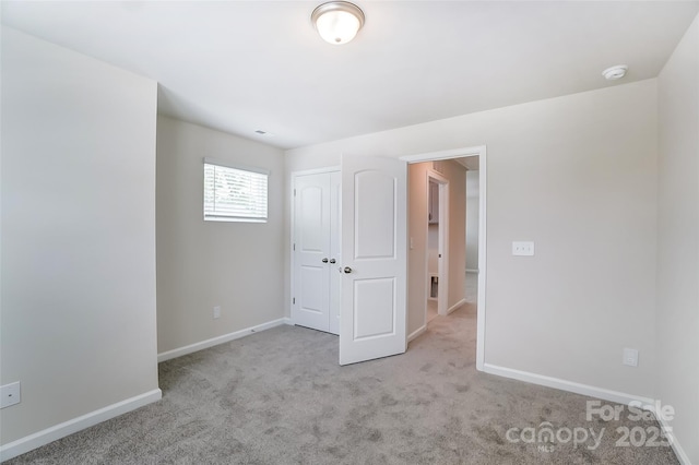 unfurnished bedroom featuring light carpet and a closet