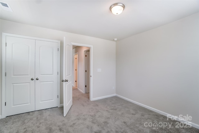 unfurnished bedroom with light colored carpet and a closet