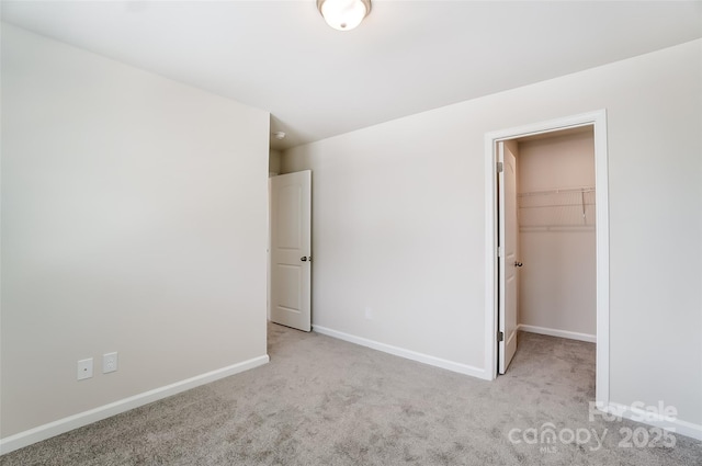 unfurnished bedroom with light carpet, a spacious closet, and a closet