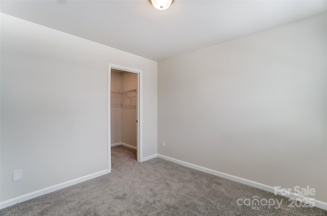 unfurnished bedroom featuring a spacious closet, light carpet, and a closet