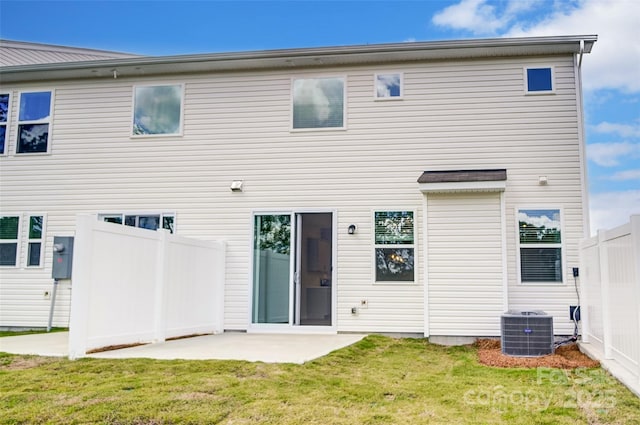 back of property with central AC unit, a patio area, and a lawn