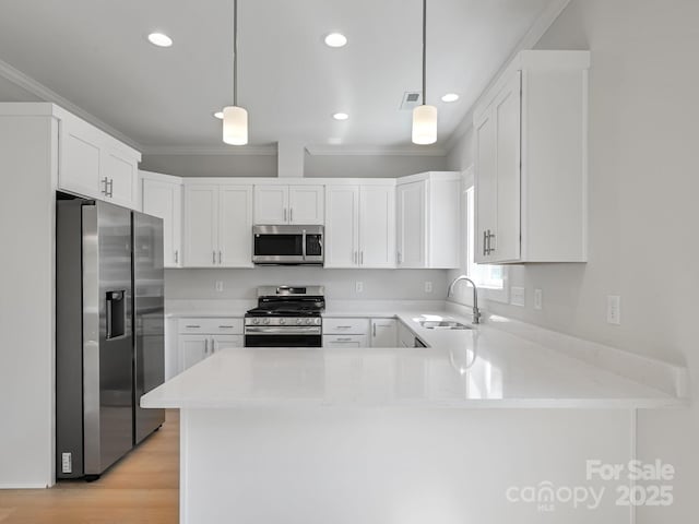 kitchen featuring a peninsula, crown molding, visible vents, appliances with stainless steel finishes, and a sink