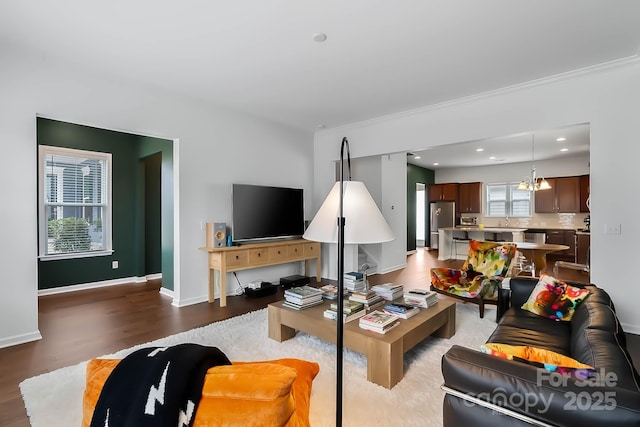 living room with an inviting chandelier, hardwood / wood-style flooring, and a healthy amount of sunlight