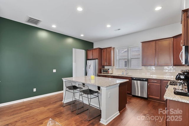 kitchen featuring light stone counters, appliances with stainless steel finishes, sink, and a kitchen island