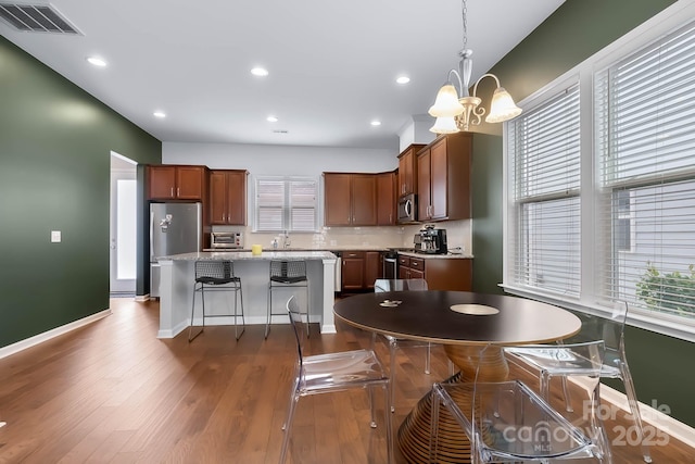 kitchen with appliances with stainless steel finishes, a kitchen island, decorative light fixtures, dark hardwood / wood-style flooring, and a notable chandelier