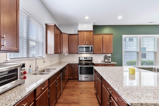 kitchen featuring stainless steel appliances, sink, light stone counters, and decorative backsplash