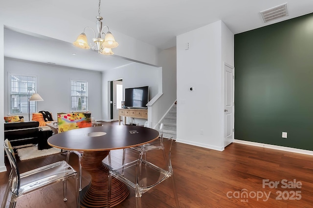 dining space featuring dark wood-type flooring and a chandelier