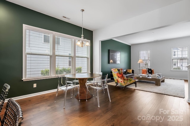 dining space with dark wood-type flooring and a chandelier