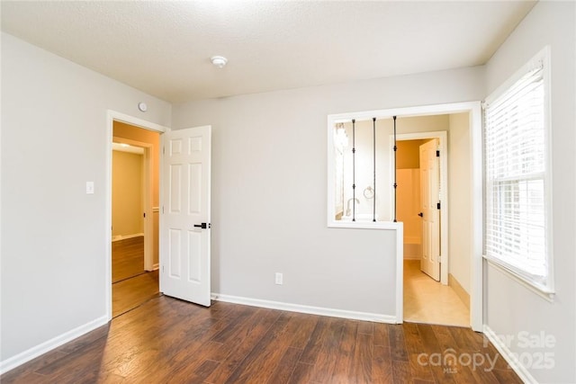 unfurnished bedroom with multiple windows and dark hardwood / wood-style flooring