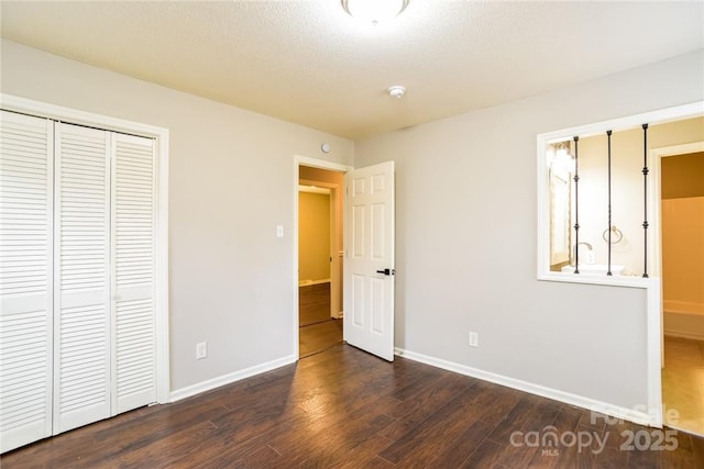 unfurnished bedroom featuring dark wood-type flooring, a textured ceiling, and a closet