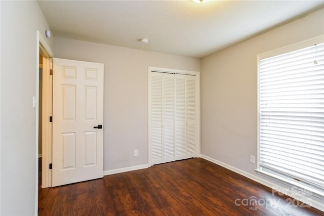 unfurnished bedroom with dark wood-type flooring and a closet