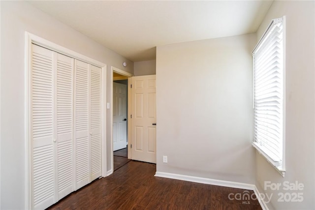 unfurnished bedroom featuring dark wood-type flooring and a closet