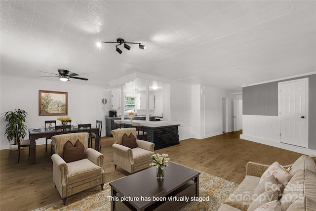 living area with dark wood-style floors, a ceiling fan, and crown molding