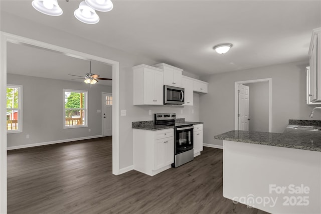 kitchen with appliances with stainless steel finishes, dark wood-type flooring, baseboards, and a sink
