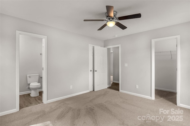 unfurnished bedroom featuring connected bathroom, baseboards, carpet flooring, and a walk in closet