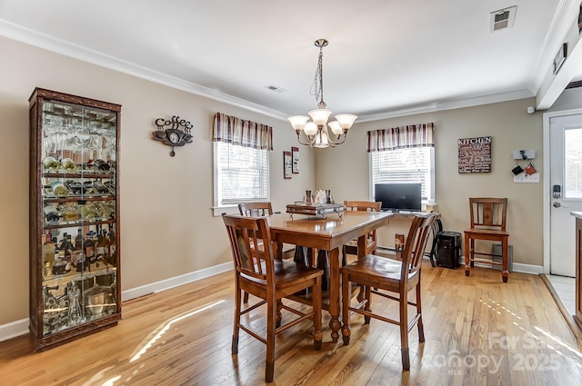 dining area featuring light hardwood / wood-style flooring, crown molding, a wealth of natural light, and a chandelier