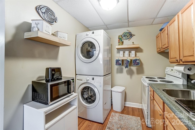 laundry area featuring sink, light hardwood / wood-style flooring, and stacked washer / dryer