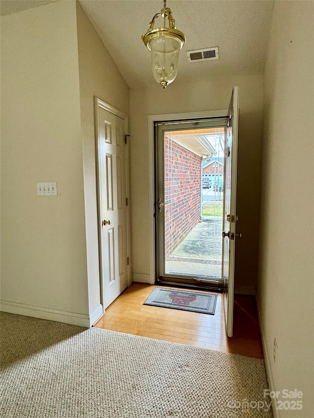 entryway with a textured ceiling and light hardwood / wood-style flooring