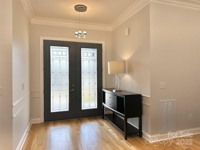 foyer entrance featuring ornamental molding, light wood-type flooring, and french doors