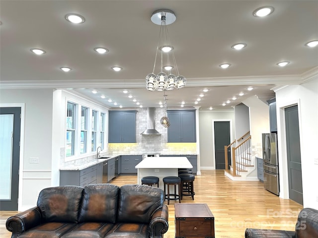 living room featuring ornamental molding, sink, and light hardwood / wood-style flooring