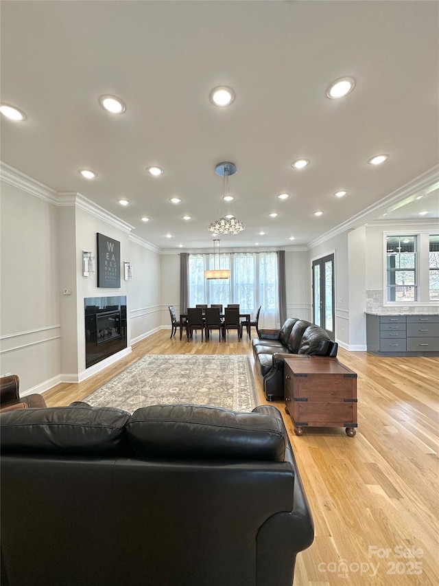 living room with ornamental molding, light hardwood / wood-style flooring, and plenty of natural light