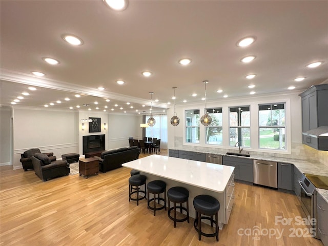 kitchen featuring a spacious island, a breakfast bar, sink, stainless steel dishwasher, and gray cabinets