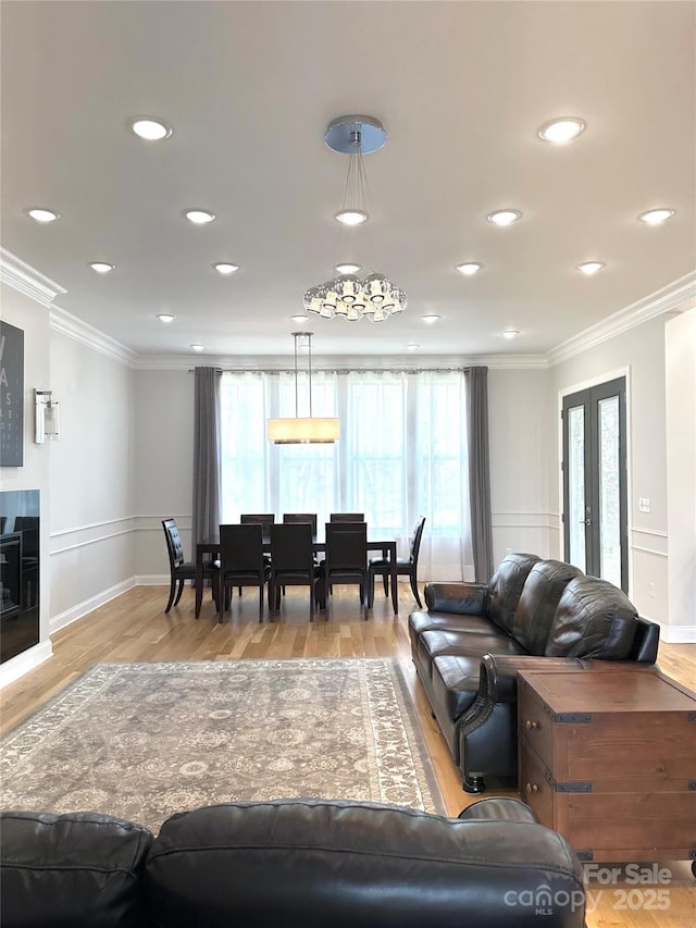 living room with a healthy amount of sunlight, ornamental molding, and light hardwood / wood-style flooring