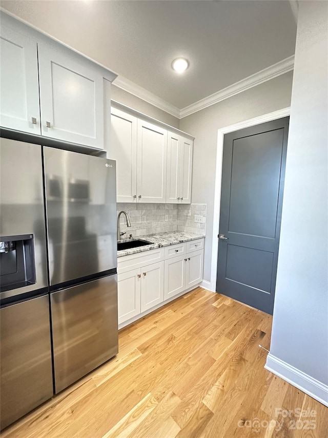 kitchen with stainless steel refrigerator with ice dispenser, sink, crown molding, light hardwood / wood-style floors, and white cabinets