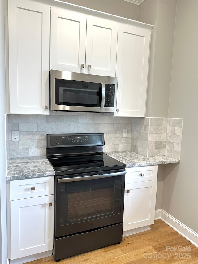 kitchen with white cabinetry, light stone countertops, black range with electric cooktop, and backsplash