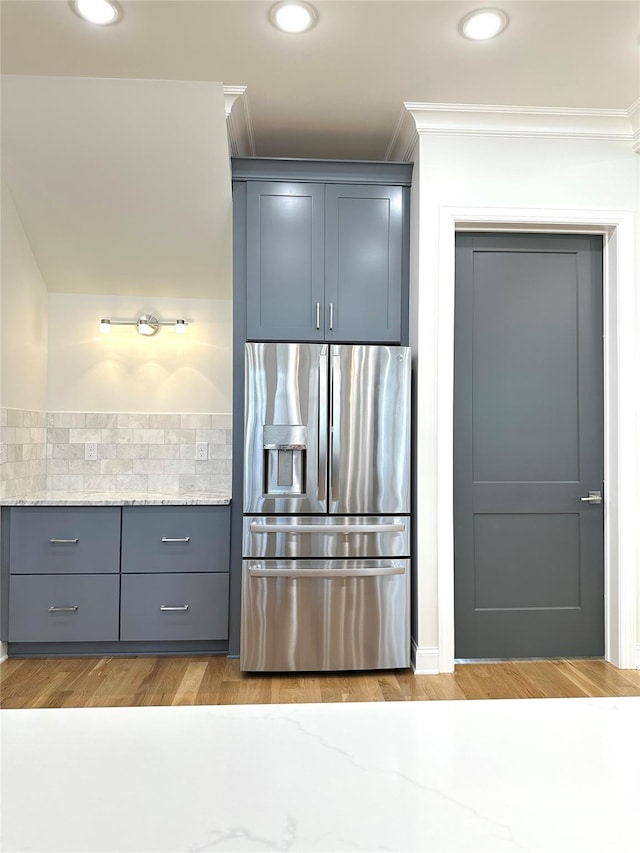 kitchen featuring ornamental molding, light hardwood / wood-style floors, light stone counters, and stainless steel fridge with ice dispenser