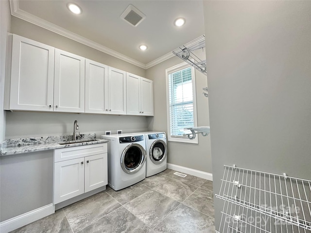 clothes washing area featuring sink, ornamental molding, washing machine and dryer, and cabinets