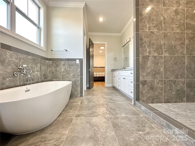 bathroom with crown molding, vanity, a bath, and tile walls