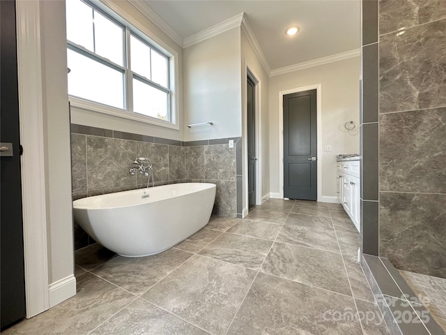 bathroom featuring ornamental molding, a bathing tub, tile walls, and vanity