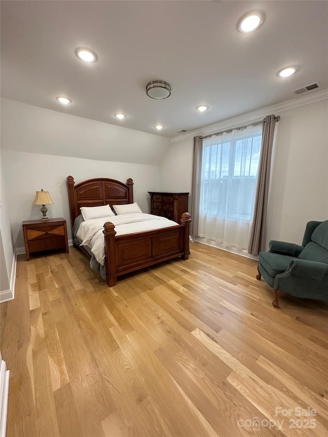 bedroom with lofted ceiling, ornamental molding, and light hardwood / wood-style floors