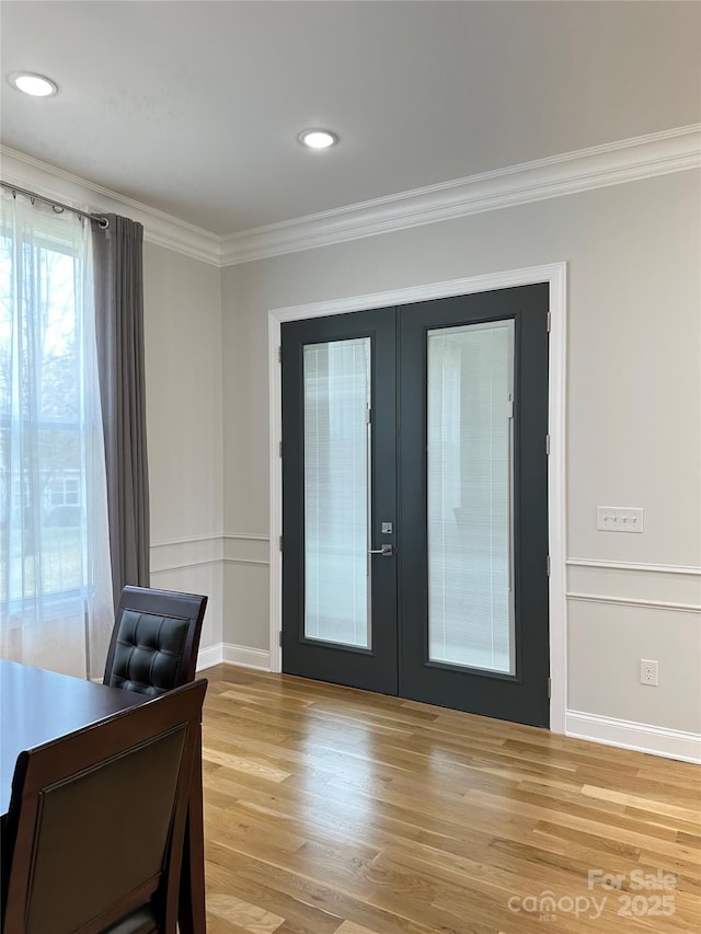 entryway with crown molding, light hardwood / wood-style floors, and french doors