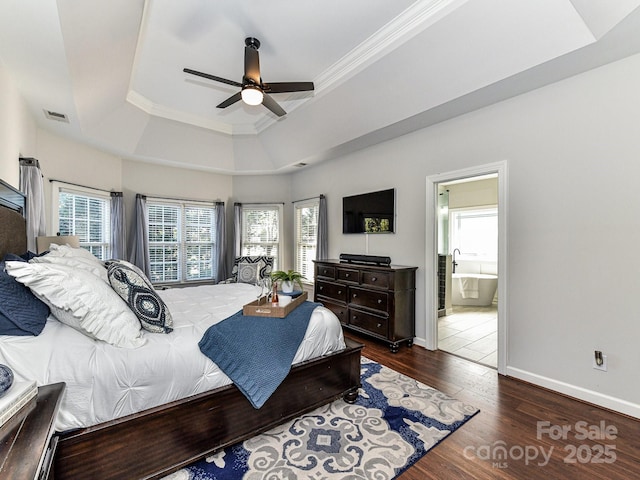 bedroom featuring crown molding, dark wood-type flooring, connected bathroom, and a tray ceiling