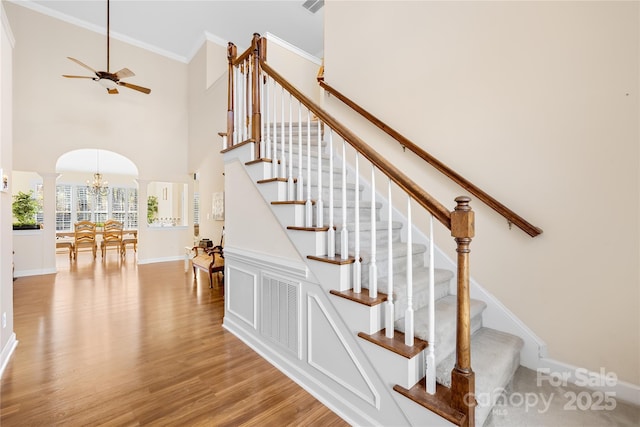 stairway featuring visible vents, arched walkways, wood finished floors, crown molding, and ornate columns